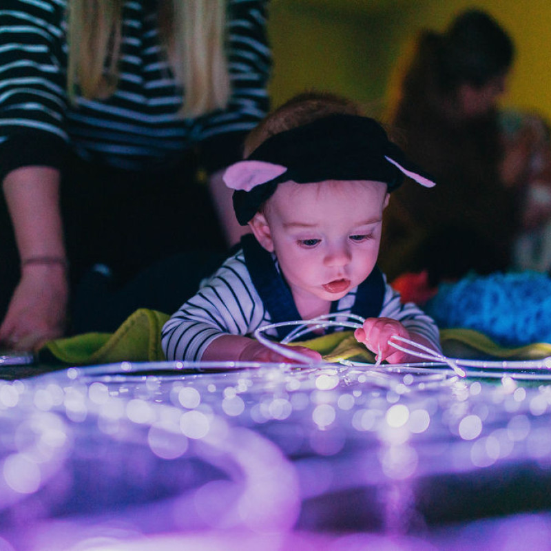 A baby doing tummy time in front of fibre optic lights